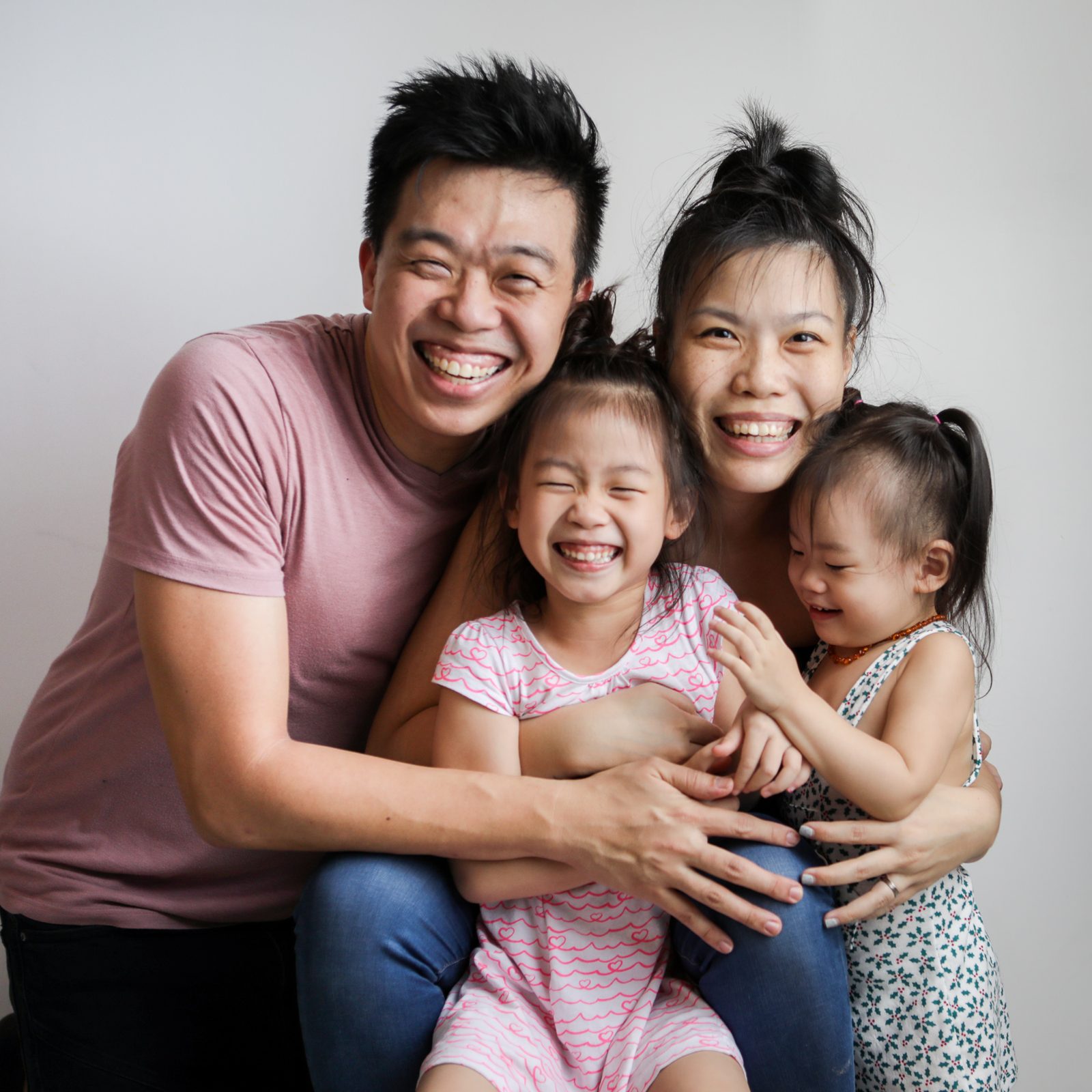 Singapore family of four laughing together during a home studio family portrait session